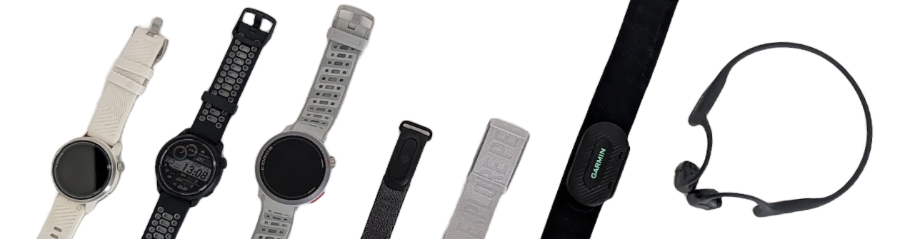Three COROS watches, a Fitbit tracker, a COROS armband heart-rate monitor, a Garmin chest strap and a pair of Shokz bone-conduction headphones, laid out in a row